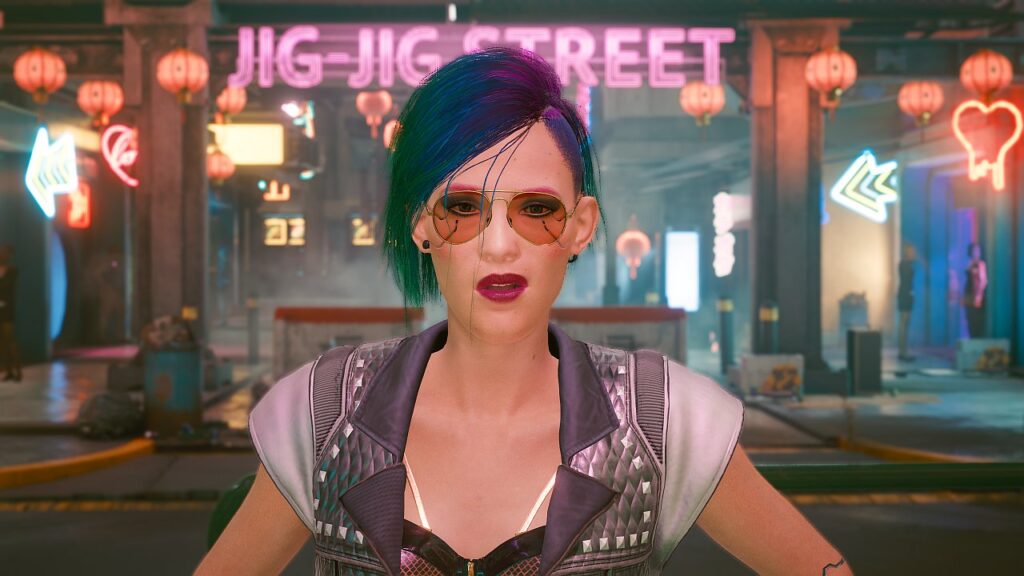 Screenshot aus dem Spiel Cyberpunk 2077 von Nastja the blogging Mox. Weibliche Cyberpunk V vor dem Eingang zum Red Light District von Night City mit verächtlichem Blick.