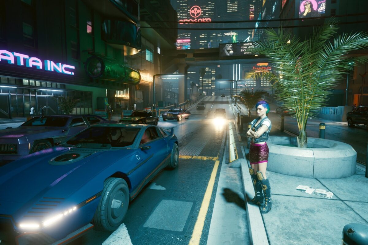 Am Rand einer vielbefahrenen Strasse im nächtlichen Night City im Neonlicht. Screenshot aus dem Spiel Cyberpunk 2077 im Blog von Nastja der Mox.