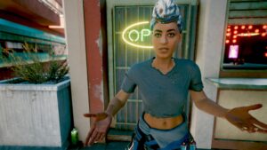 Frau mit Kopftuch und praktischer Kleidung vor einem Laden. Screenshot aus dem Spiel Cyberpunk 2077 im Blog von Nastja der Mox. The Nameless of Night City ist eine Würdigung an die Ingame-NPCs.