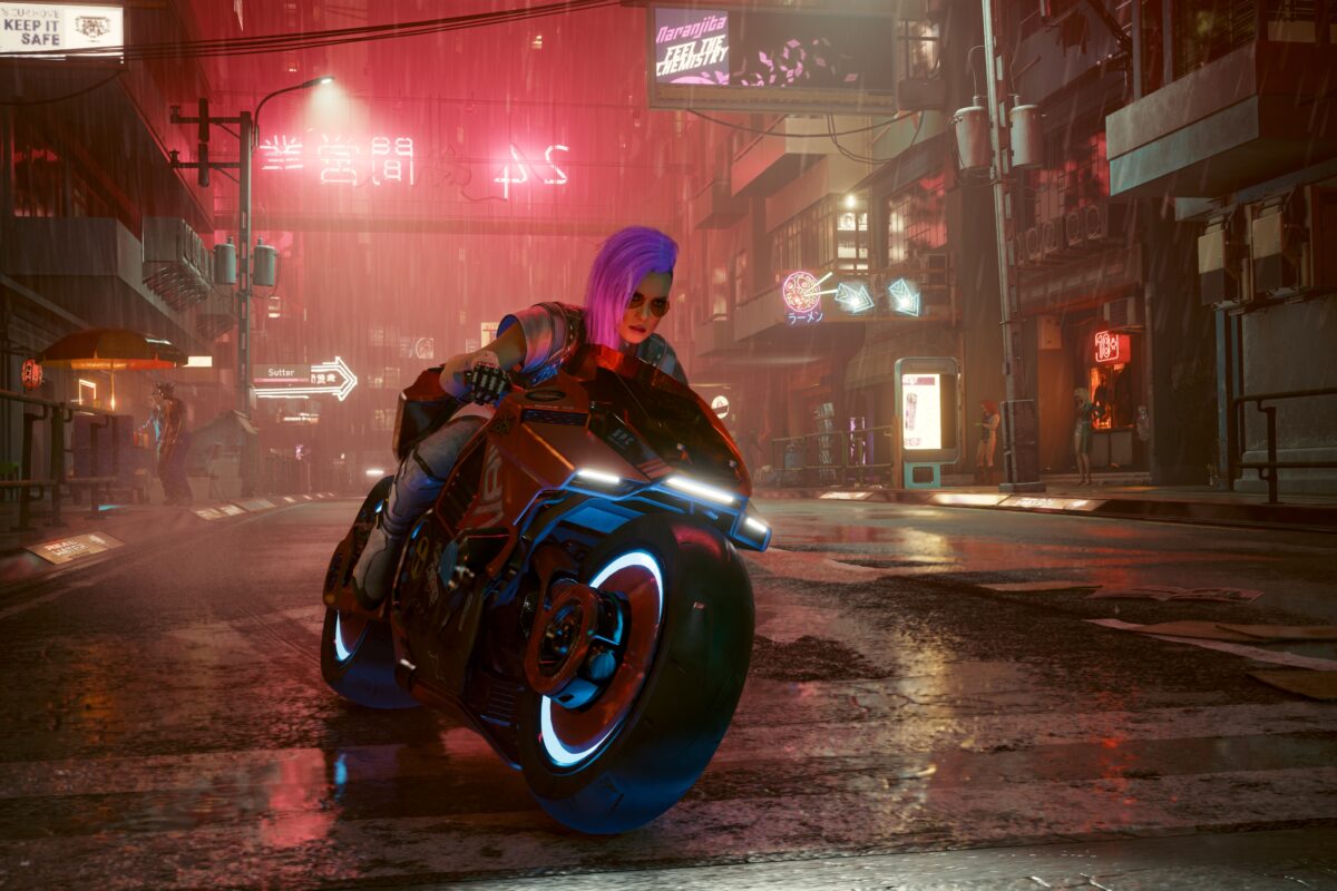 Weibliche Cyberpunk auf einem Bike durch Night City bei Nacht und Regen in rotem Neonlicht. Screenshot aus dem Spiel Cyberpunk 2077