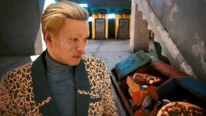 Junger Mann mit Gesichts-Cyberware und elegantem Anzug neben einer Pizza im Mülleimer. Screenshot aus dem Spiel Cyberpunk 2077