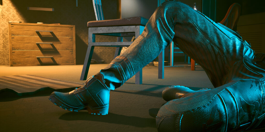 Nahaufnamhe zweier beine in Hosen und Schuhen am Boden gekauert in einem versifften Zimmer. Screenshot aus dem Spiel Cyberpunk2077