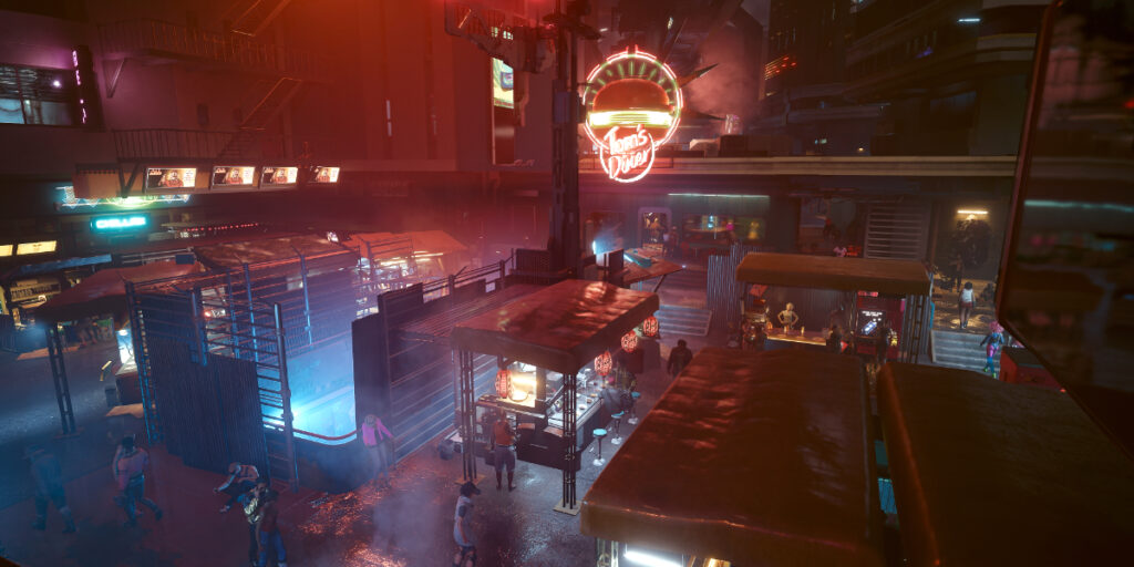 Markt in der Nacht mit Tom's Diner im Hintergrund. Screenshot aus dem Spiel Cyberpunk 2077