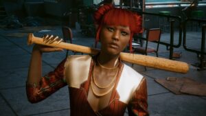 Oberkörper und Kopfbild einer POC-Frau in elegantem Kostüm mit roten Haaren und viel Goldschmuck. Auf der Schulter ein Baseballschläger aus Holz. Screenshot aus dem Spiel Cyberpunk2077