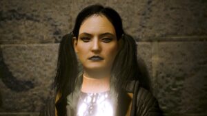 Porträt einer dunkelhaarigen Frau mit versteinerten Gesichtszügen, die sich an eine Wand lehnt. Screenshot aus dem Spiel Cyberpunk 2077.