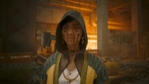 Dunkelhaarige junge Frau in Kapuzenjacke mit Goldschmuck vor einem Elendsviertel von Dogtown. Screenshot aus dem Spiel Cyberpunk2077.